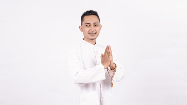 Young Asian Muslim man with greeting and welcoming gesture in Ramadhan
