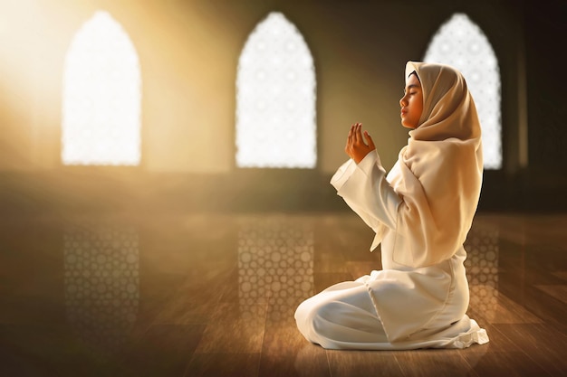 Young asian muslim teenage girl praying in the mosque window arch eid adha mubarak concept