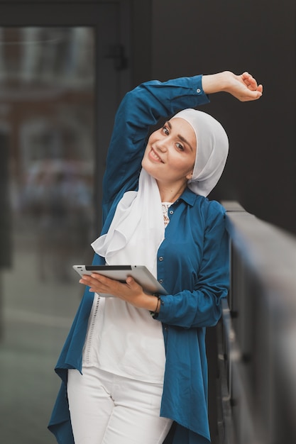 Young asian muslim woman in head scarf smile with mobile tablet