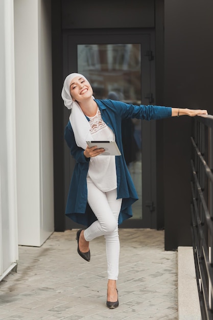 Young asian muslim woman in head scarf smile with mobile tablet.