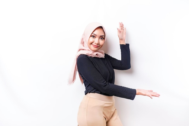 Young Asian Muslim woman smiling while pointing to copy space beside her