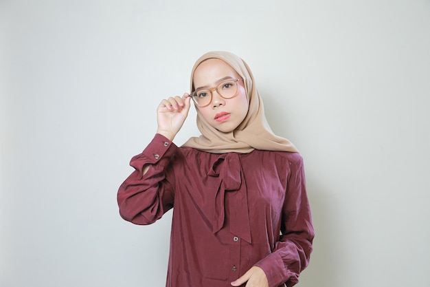 Young Asian Muslim woman wearing glasses looking confident and happy over white background