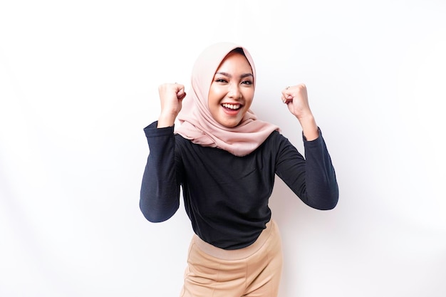 A young Asian Muslim woman with a happy successful expression wearing a hijab isolated by white background