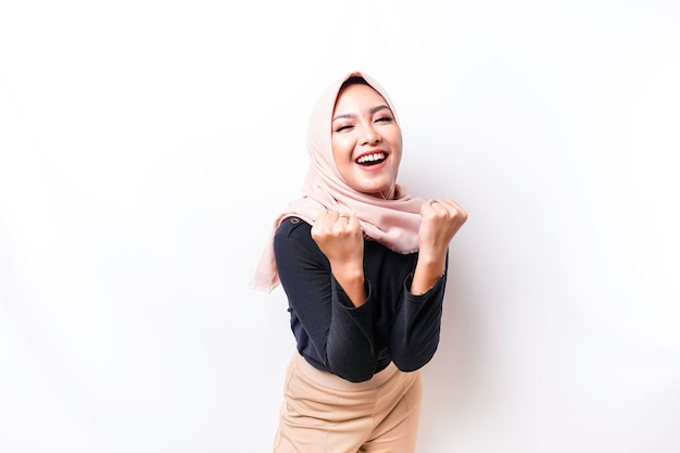 白い背景で隔離されたヒジャブを身に着けている幸せな成功した表現を持つ若いアジアのイスラム教徒の女性