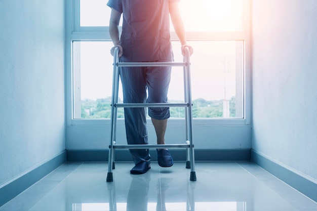 Young asian physical therapist working with senior woman on walking with a walker