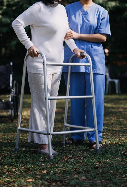 Young asian physical therapist working with senior woman on walking with a walker