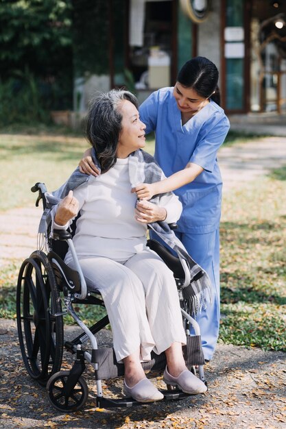 Young asian physical therapist working with senior woman on walking with a walker