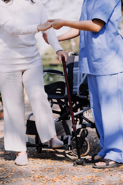 Foto giovane fisioterapeuta asiatica che lavora con una donna anziana a camminare con un passeggino