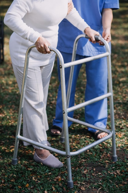 Foto giovane fisioterapeuta asiatica che lavora con una donna anziana a camminare con un passeggino