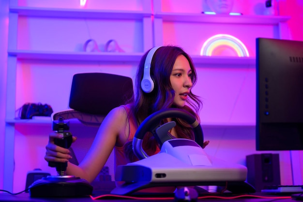 La giovane bella donna asiatica pro gamer ha live streaming giocando al videogioco gioco di corse a casa