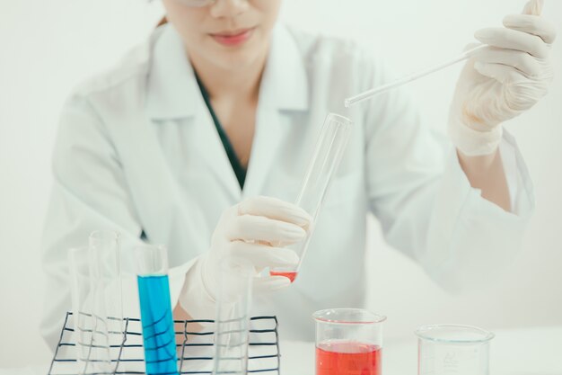 Young Asian scientist working in the lavatory with test tubes and other equipment to discover new drugs