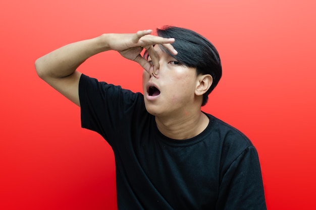 young asian showing an expression of dislike and disgust isolated over red background.