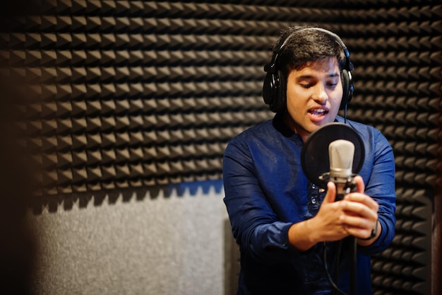 Young asian singer man with microphone recording song in record music studio.