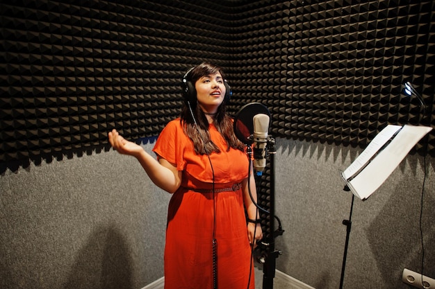 Фото Молодой азиатский певец с песней записи микрофона в студии звукозаписи.