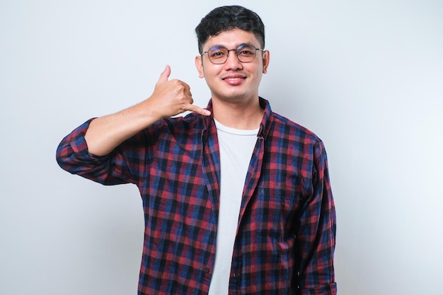 Young asian smiling doing phone gesture with hand and fingers like talking on the telephone Communicating concepts