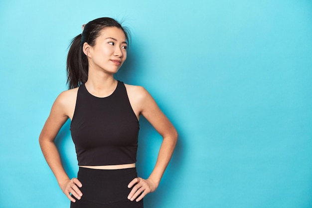 Young Asian sportswoman studio shot on blue background