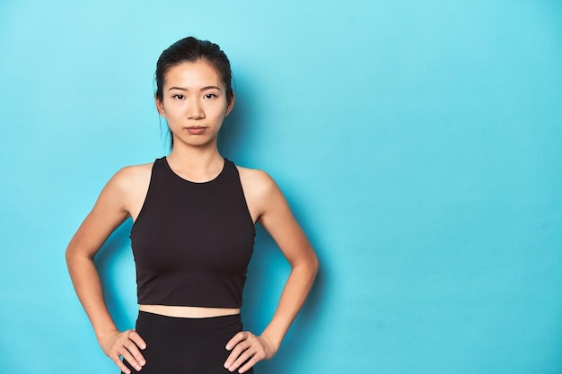 Young Asian sportswoman studio shot on blue background