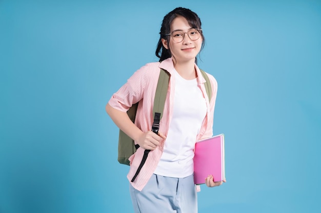 Young Asian student on blue background