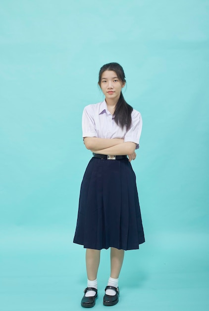 水色のスタジオの孤立した背景に学生の制服を着た若いアジアの学生の女の子の高校