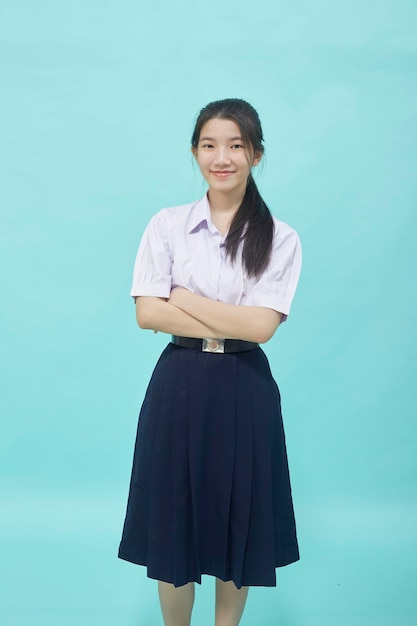 水色のスタジオの孤立した背景に学生の制服を着た若いアジアの学生の女の子の高校
