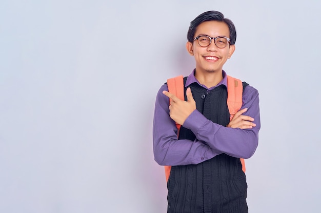 Young asian student man cheerful with a smile on his face
pointing with his hand and finger up to the side with a happy and
natural expression isolated on gray background