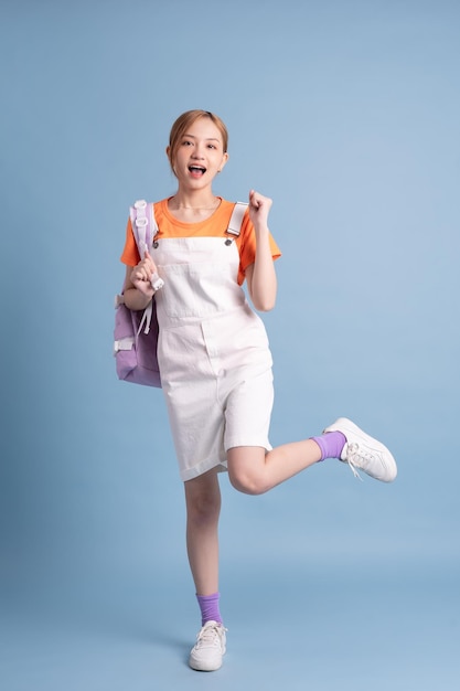 Young Asian student posing on blue background