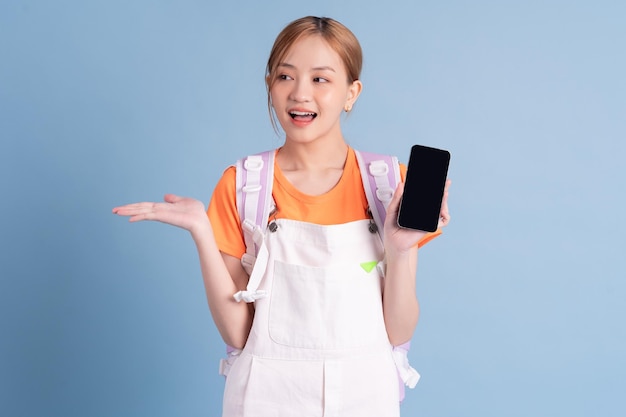 Young Asian student posing on blue background