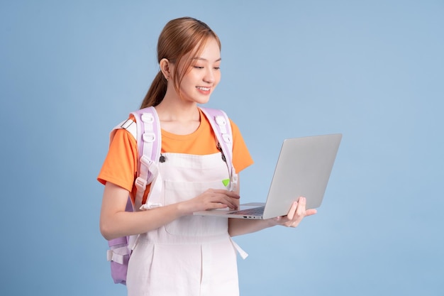 Young Asian student posing on blue background