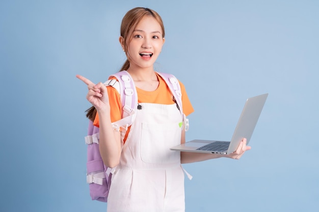 Young Asian student posing on blue background