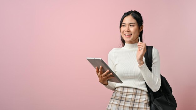 Young asian student wearing white sweater using tablet on pink isolate background person