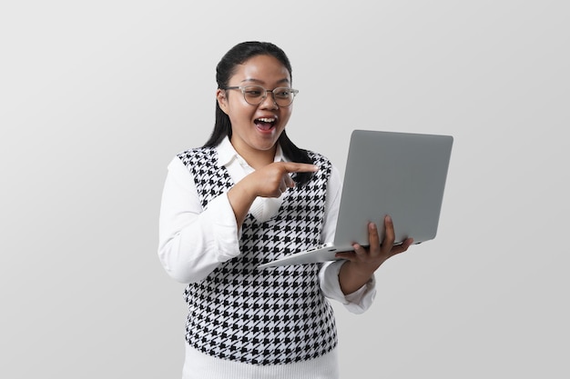 Young Asian student woman holding laptop smiling happy pointing with hand and finger