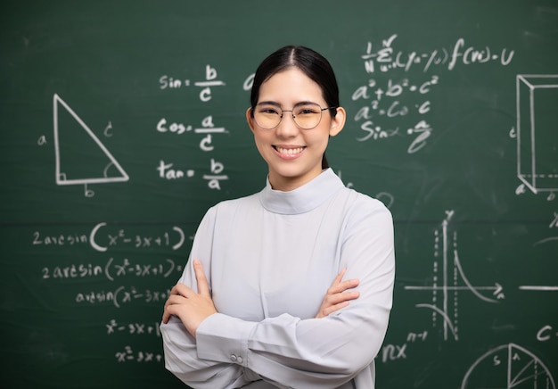 Young asian teacher woman teaching standing with arms crossed\
video conference with student female teacher training the\
mathematics in classroom blackboard from online course