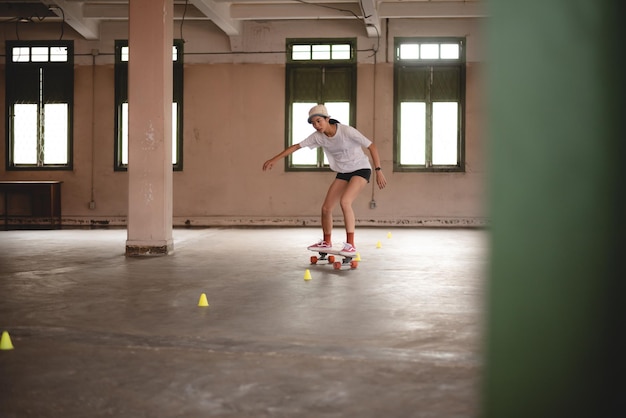 Молодая азиатская девочка-подросток, играющая на скейтборде в городском спорте, счастливый и веселый образ жизни со скейтбордингом