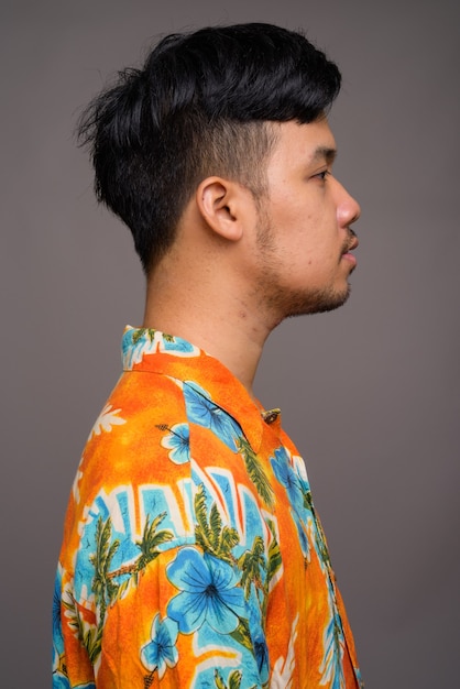 Young Asian tourist man ready for vacation against gray