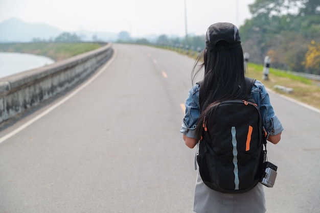 Young asian traveler with backpack looking direction on the road while traveling during holiday vacation