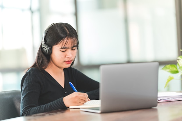 A young Asian university student wearing headphones to study online at home,During the time of the virus outbreak and did not attend university.