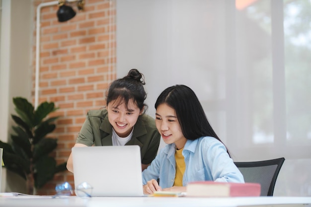 학습을 공부하는 젊은 아시아 대학생들은 컴퓨터 작업에 대해 토론합니다.