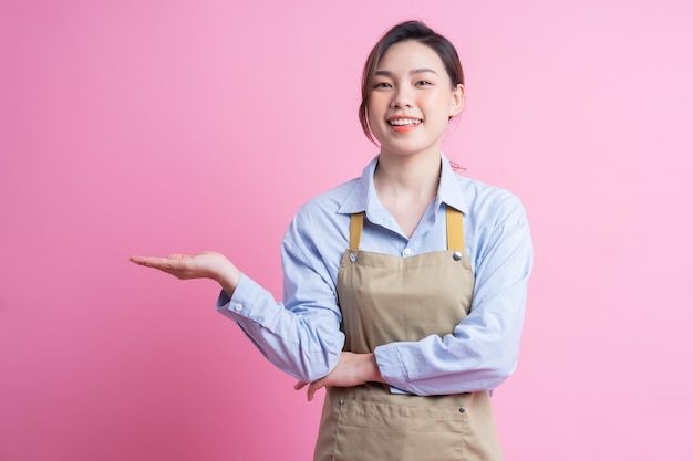 Молодая азиатская официантка стоит на розовом фоне