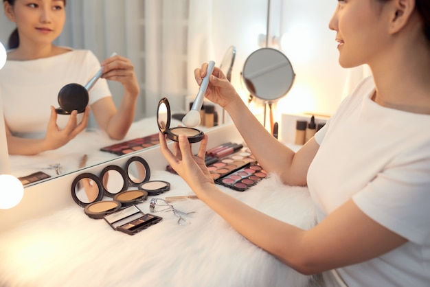 Young Asian woman applying powder with big brush. Cosmetics concept