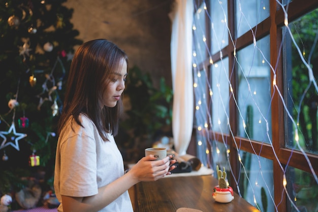 젊은 아시아 여성은 카페에서 크리스마스 이브를 축하하는 것을 즐깁니다. 커피 카페에서 보여주는 크리스마스 파티 밝은 배경