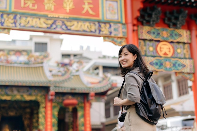 Foto giovane viaggiatore asiatico dello zaino della donna che gode del mercato dell'alimento della via della città della cina a bangkok tailandia viaggiatore che controlla le strade laterali