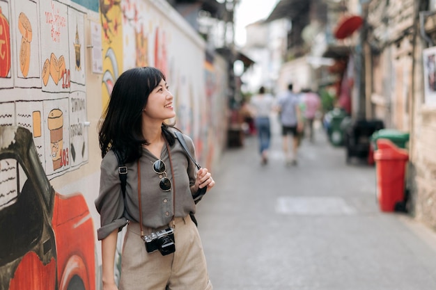 通りの文化的な地元の場所と笑顔を楽しむアジアの若い女性のバックパック旅行者横道をチェックする旅行者