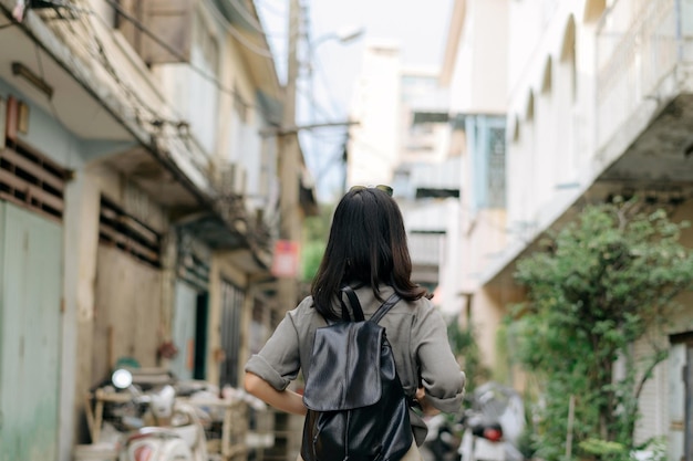 通りの文化的な地元の場所を楽しむアジアの若い女性のバックパック旅行者脇道をチェックする旅行者