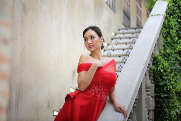 Young Asian Woman in a beautiful red dress looking at camera with smile. Fashion model, bride or pre-wedding concept.