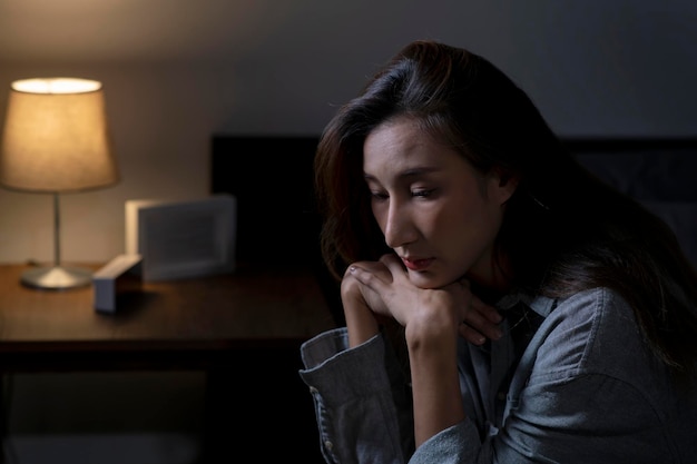 Young Asian woman in bedroom feeling sad tired and worried suffering depression in mental health woman sitting in bed cannot sleep from insomnia