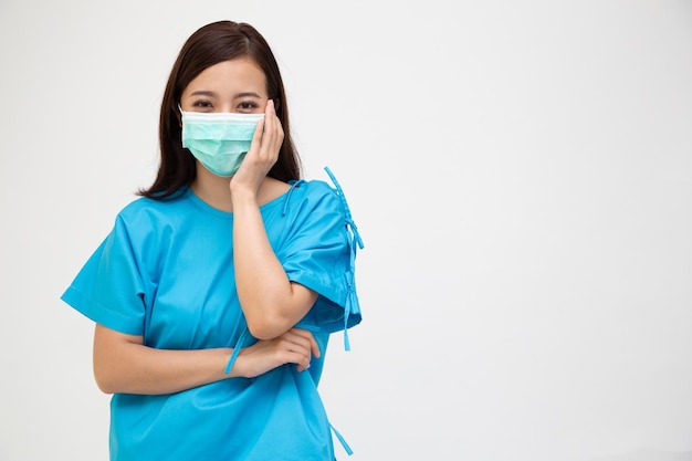 Young Asian woman in blue patient uniform wearing face mask and got toothache isolated on white background