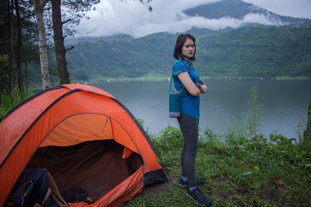 Young asian woman camping or picnic in forest lake.