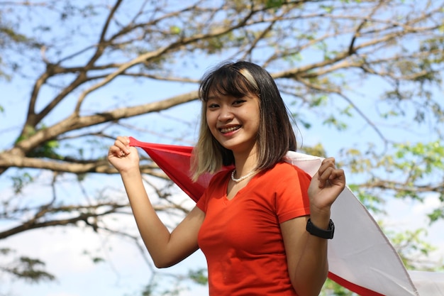 young asian woman carrying indonesian flag