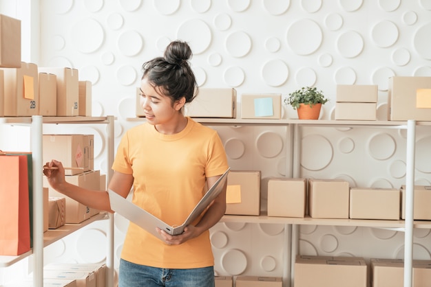 young Asian woman  checking goods on stock shelf at warehouse