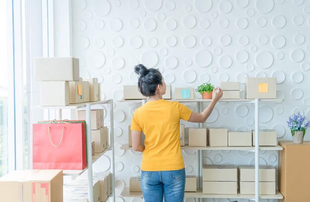 young Asian woman  checking goods on stock shelf at warehouse